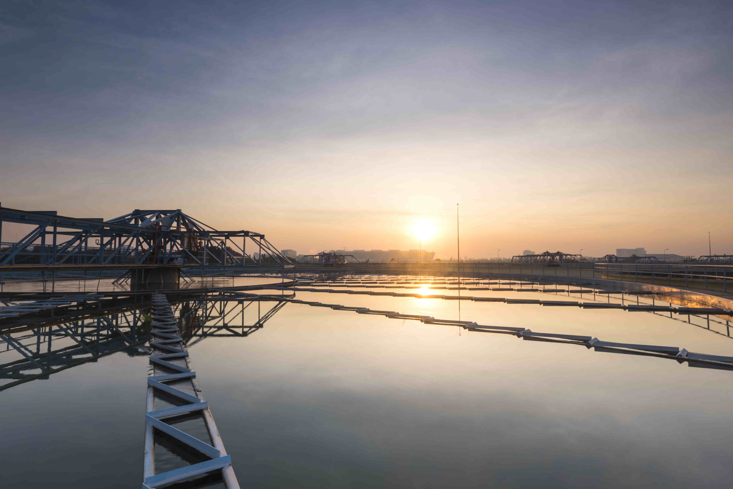 Steel bridge over water with a sunset in the distance